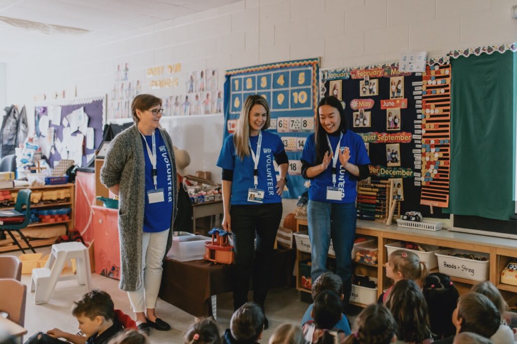 Three Ontario SPCA volunteers in blue shirts speaking to a group of young students in a classroom