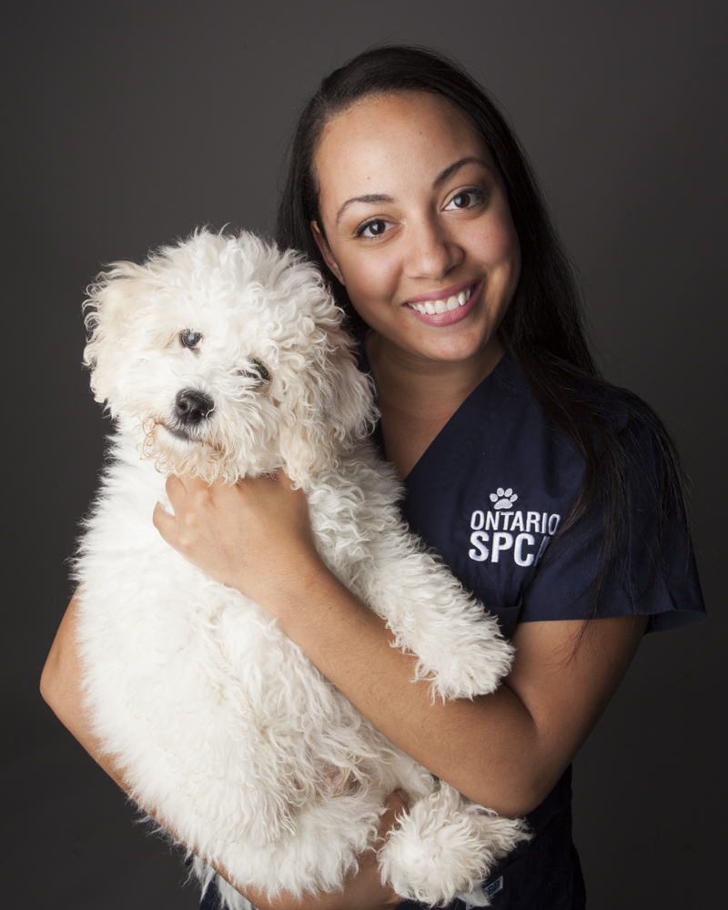 Smiling woman in Ontario SPCA uniform holding a fluffy white dog