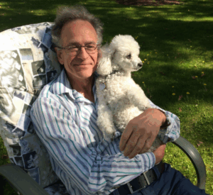 A man seated in a chair, enjoying the company of a dog.