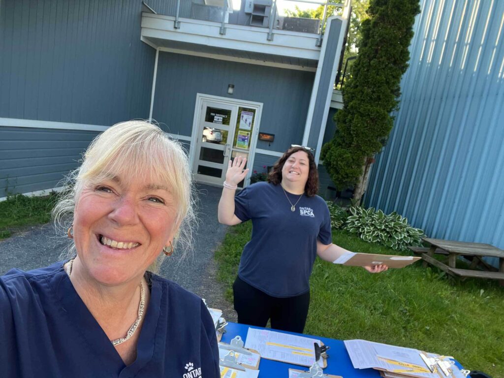 Ontario SPCA team members smiling outdoors at a check-in table for a mobile clinic event.