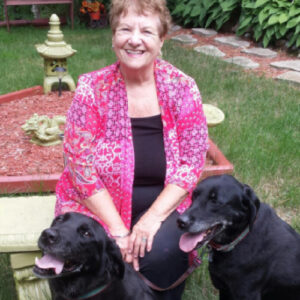 woman sitting outside in garden with black dog