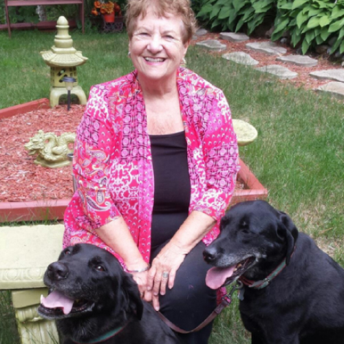 woman sitting outside in garden with black dog