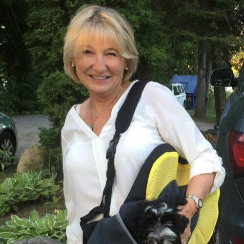 woman holding a dog in a bog, smiling at camera