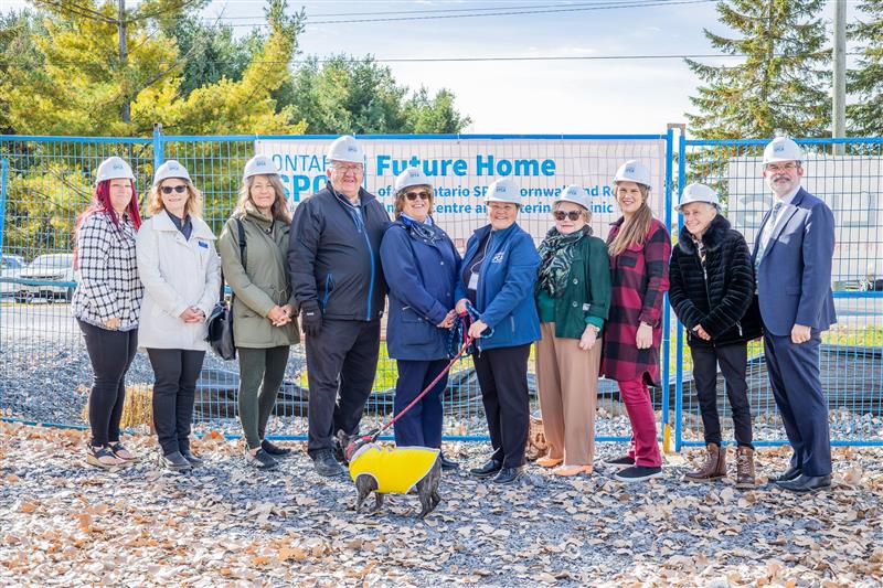 A group of people standing together with hard hats on, breaking ground on new build.