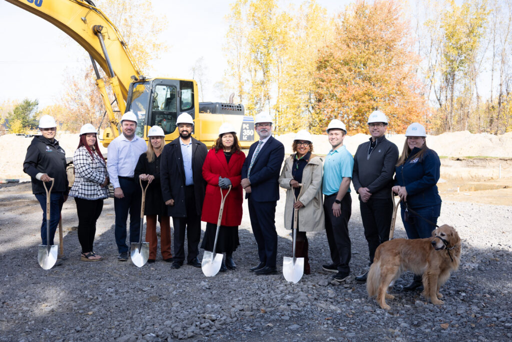 Ground breaking shot with people and an excavator, in Cornwall.