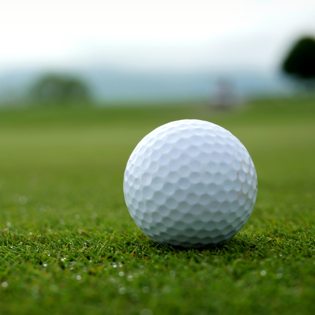golf ball sitting on golf green with blurred course in background