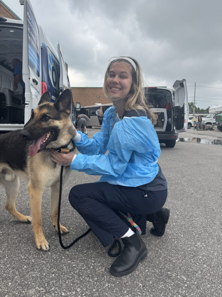 Volunteer crouching beside German Shepherd dog in front of Ontario SPCA mobile clinic unit