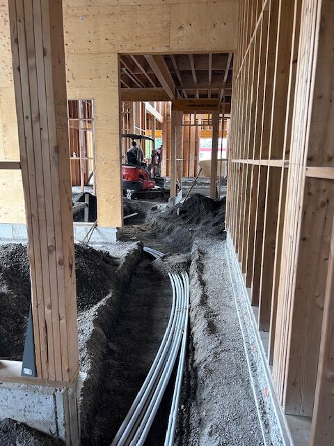 Interior construction view with electrical conduit and utility lines routed through timber-framed walls