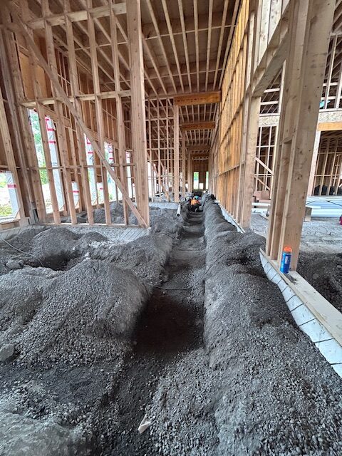 Interior construction trenches dug for underground utilities with timber frame and structural supports visible overhead